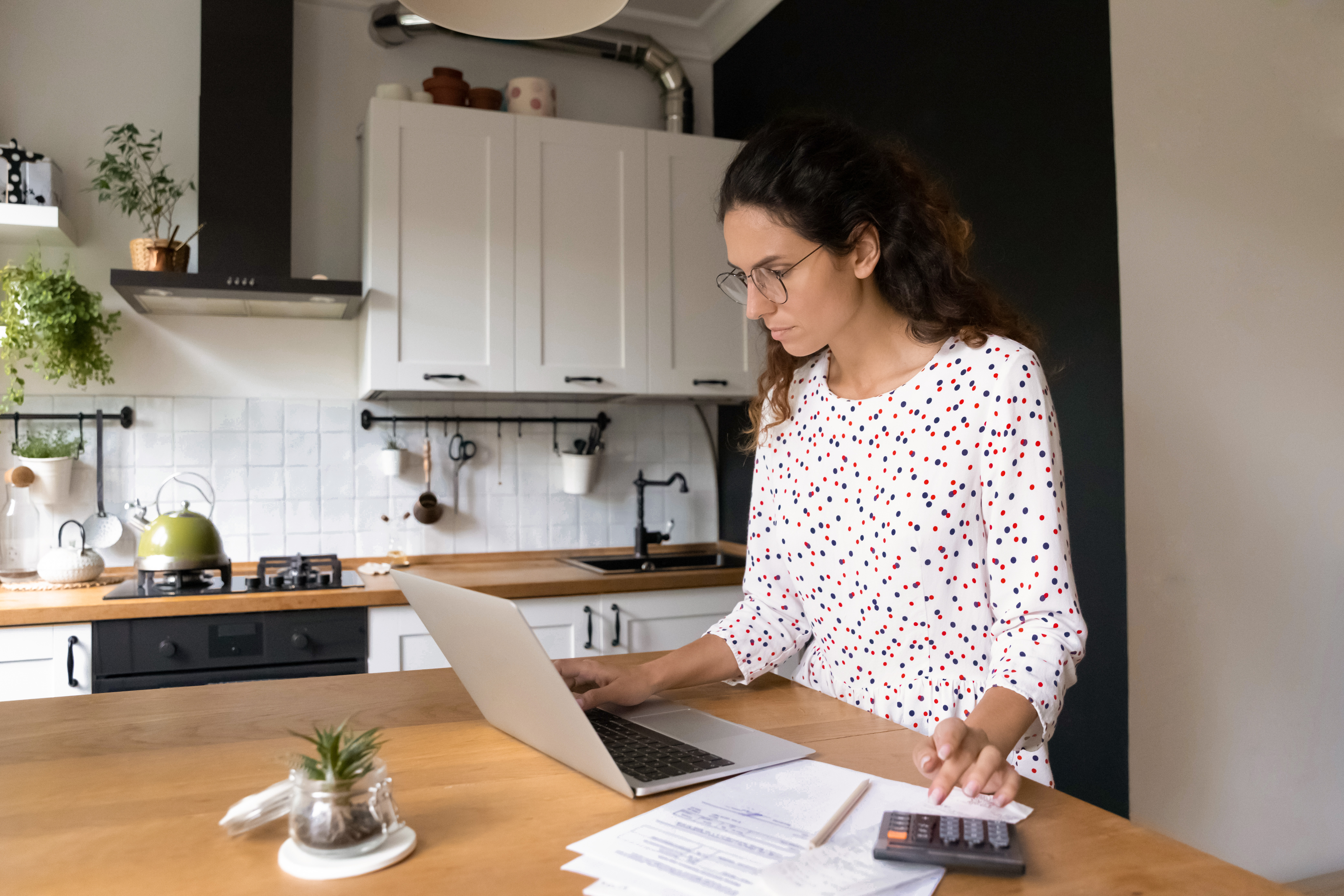 En kvinne sitter med PC og kalkulator