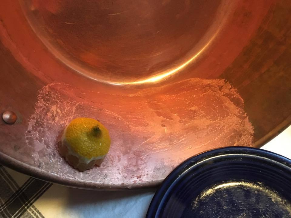 Her har vi en veldig oksidert syltetøykjele som i tillegg er brukt på gass. Vi dypper den halve sitronen i salt og gnir.